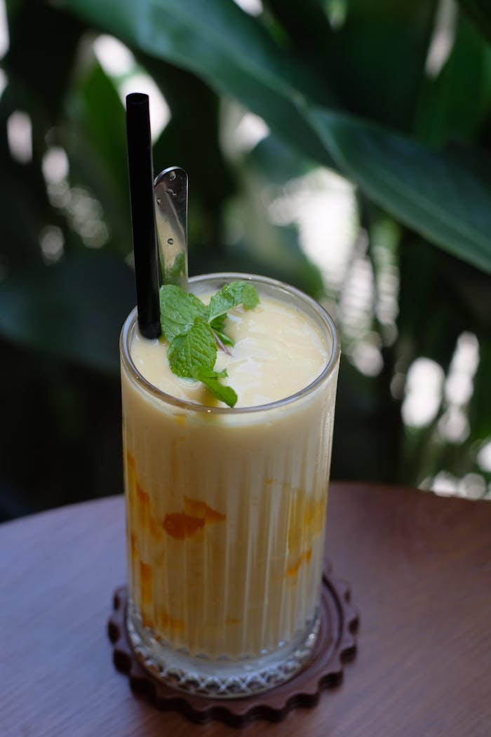 services-03 Close-up shot of a mango smoothie with mint garnish in a glass, ideal for summer vibes.