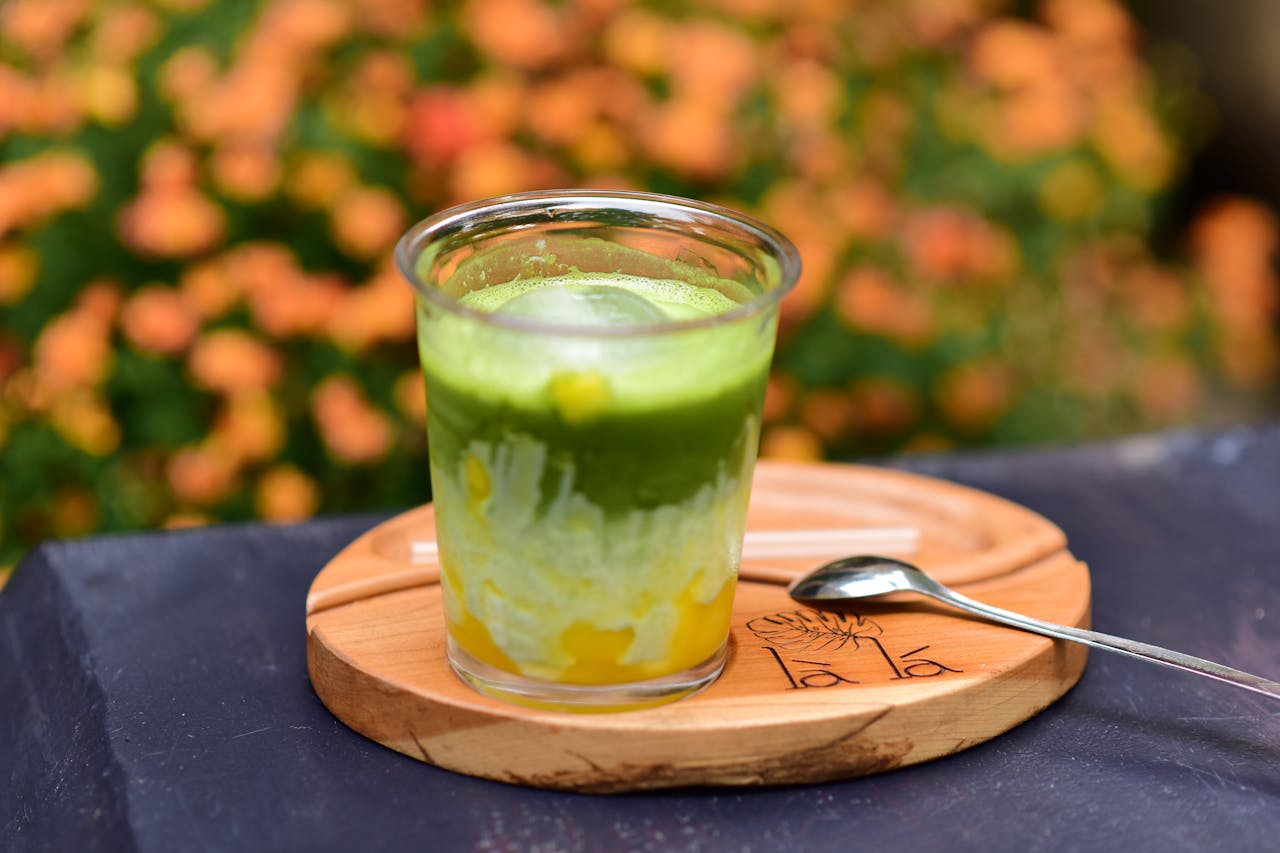 services-01 A vibrant glass of iced matcha green tea with orange flowers in the background, ideal for outdoor dining settings.