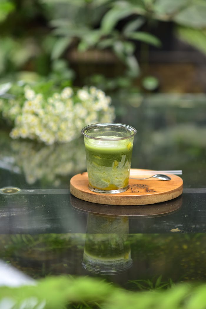 why-choose-us A glass of iced matcha latte on a wooden coaster, perfect for a refreshing break.