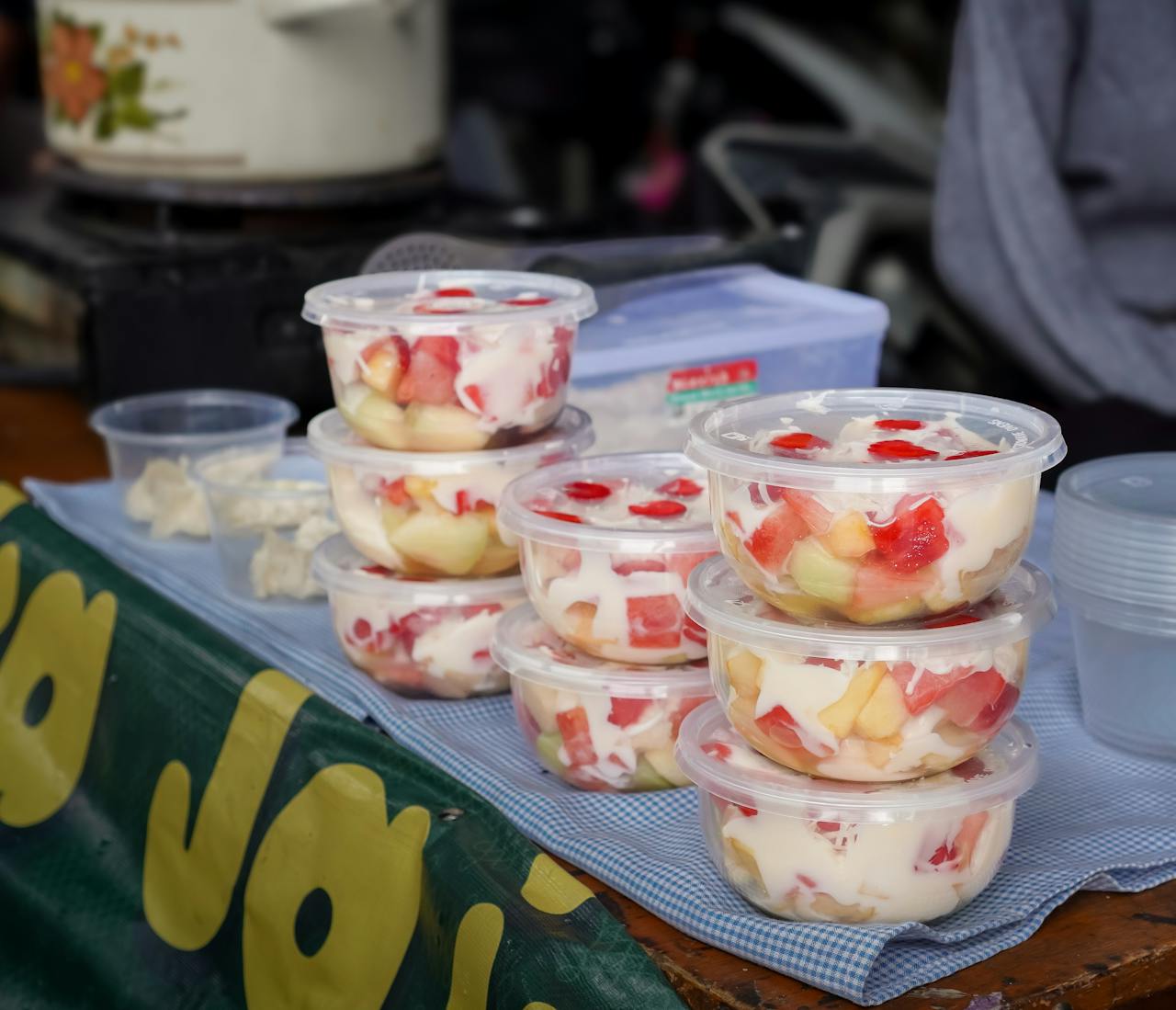 services-img Colorful fruit salad cups with cream on display at an outdoor market stand.