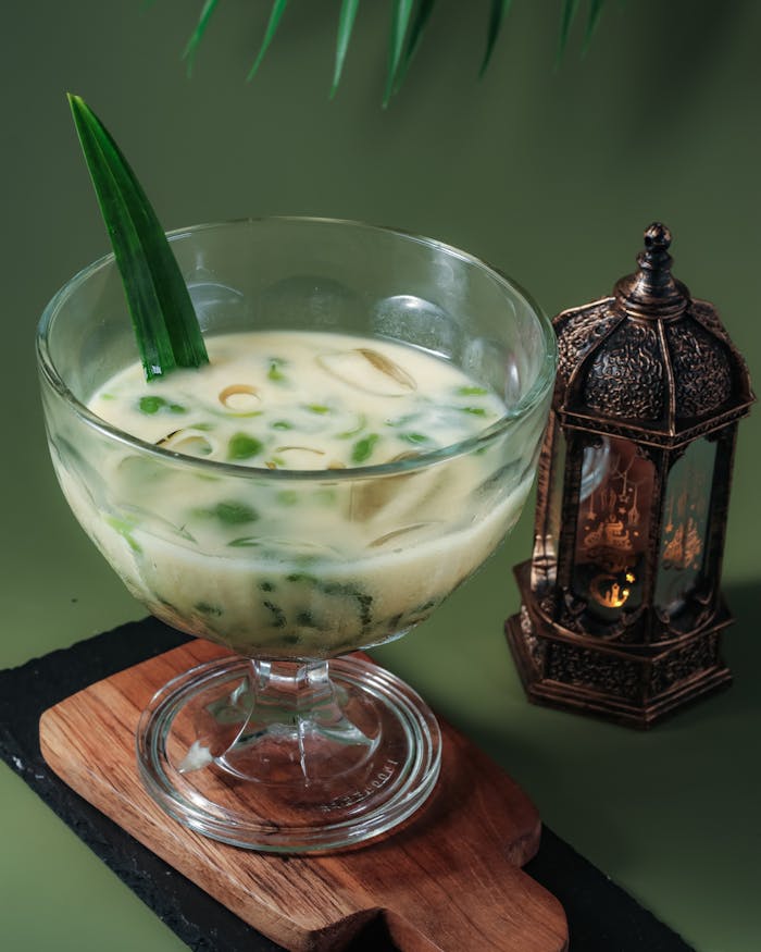 services-02 Glass of Indonesian Es Cendol with a decorative lantern on a wooden tray.
